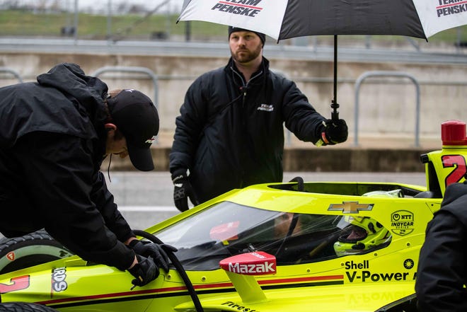 Team members keep Simon Pagenaud dry during a break in action of IndyCar testing Tuesday at he Circuit of the Americas. Driving was halted for more than a day-and-a-half by consistent rains. [LOLA GOMEZ/AMERICAN-STATESMAN]