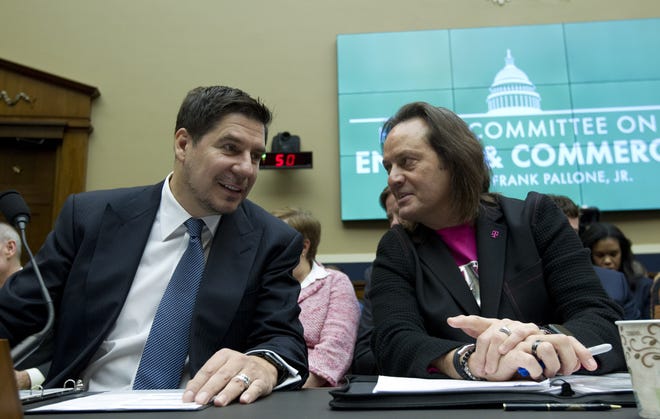 FILE - In this Feb. 13, 2019, file photo Sprint Corporation Executive Chairman Marcelo Claure, left, speaks with T-Mobile US CEO and President John Legere during the House Commerce subcommittee hearing on Capitol Hill in Washington. A federal judge has removed a major obstacle to T-Mobile's $26.5 billion takeover of Sprint, as he rejected claims by a group of states that the deal would mean less competition and higher phone bills. (AP Photo/Jose Luis Magana, File)