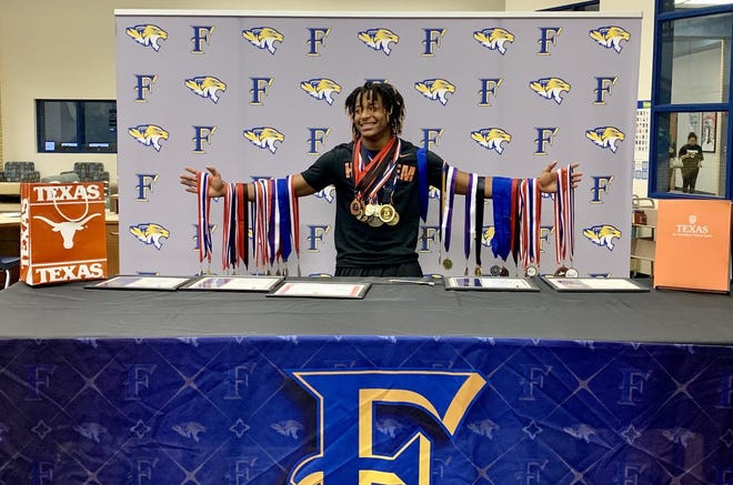 Frenship’s Daniel Garland displays medals he’s accumulated over two seasons of running track after signing his national letter of intent Wednesday to run for the University of Texas at Frenship High School in Wolfforth. [Alexis Cubit/A-J Media]
