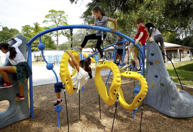 Kids play on a playground structure during the opening of the new J.J. Finley Park in September. The city is looking to rename the park. [Brad McClenny/Staff photographer]