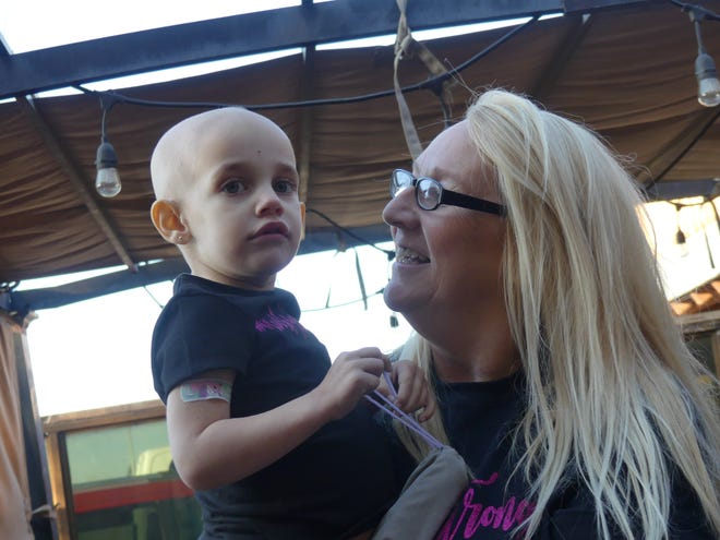 Cancer warrior Kinsley Schreiner, 2, with her grandmother, Kathy Harris at the annual Cues for a Cure 8 Ball Tournament and Fundraiser on Saturday at the Rusty Bull in Apple Valley. [RENE RAY DE LA CRUZ/DAILY PRESS]