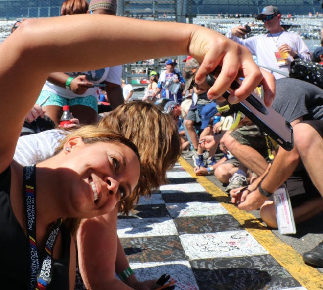 A race fan takes a selfie on the start / finish line before the start of the 2018 Daytona 500 at Daytona International Speedway.  [N-J/David Tucker]