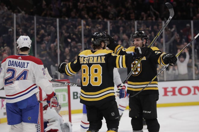 Boston Bruins right wing David Pastrnak (88) is congratulated by Patrice Bergeron after his third goal of the game during the second period of an NHL hockey game in Boston, Wednesday, Feb. 12, 2020. At left is Montreal Canadiens center Phillip Danault (24). (AP Photo/Charles Krupa)