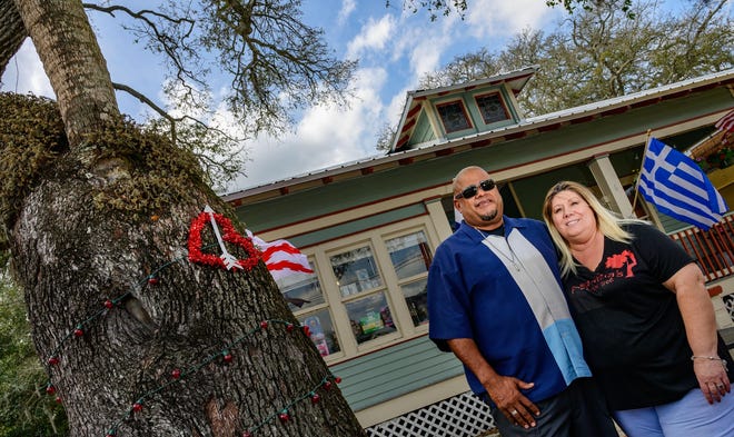 Frankie and Margaret Espinal stand beside a “Love Tree,” a palm tree growing out of the heart of an oak tree, in the front yard of their Love Tree Café on Cordova in St. Augustine last week. [PETER WILLOTT/THE RECORD]