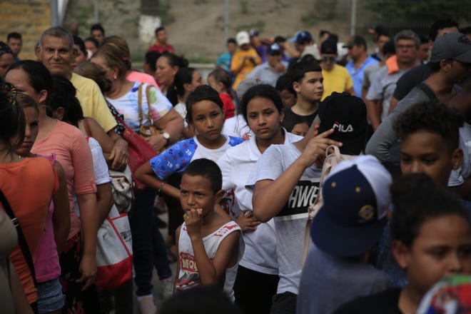 Migrants from countries including Honduras, Cuba, Venezuela and Nicaragua, line up to receive a meal donated by volunteers from the U.S. at the foot of the bridge in Matamoros that crosses to Brownsville. Hundreds of migrants, some of whom have been in line for months, are awaiting their turn to request asylum in the U.S. [AP Photo/Rebecca Blackwell]