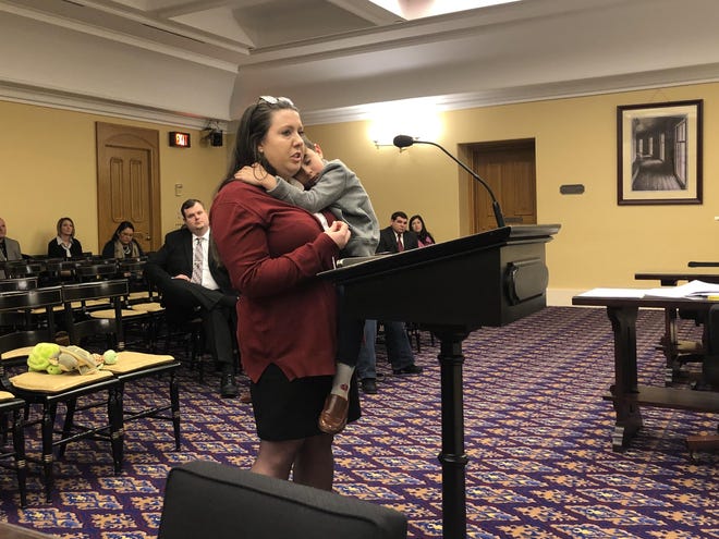 Katie Swilinski of Toledo, holding her son, Oliver, testifies Friday before a conference committee about the importance of the EdChoice Scholarship program to her family. [Anna Staver/Dispatch]