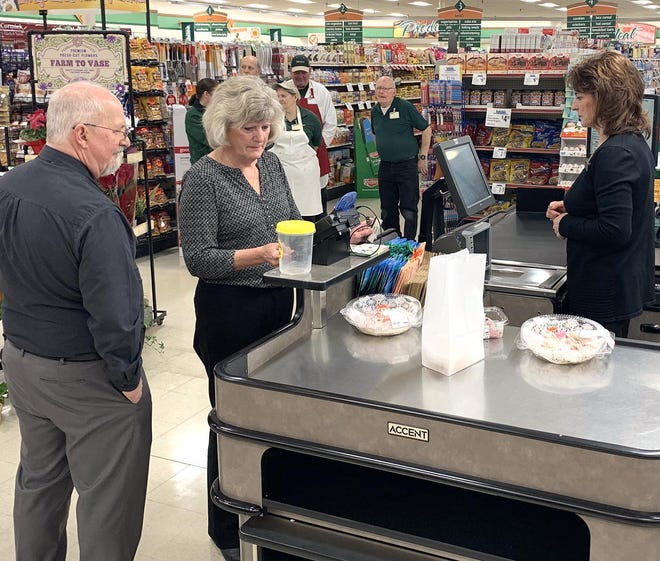 Dave Marks, left, watches as his wife Kathy officially becomes the first customer at Jubilee Foods under his ownership, Thursday morning. [JACOB WICHTOWSKI/THE LEADER]