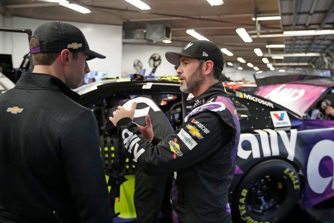 Jimmie Johnson, right, talks with a crew member in his garage after a practice session for the NASCAR Daytona 500 auto race at Daytona International Speedway, Friday, Feb. 14, 2020, in Daytona Beach, Fla. (AP Photo/John Raoux)