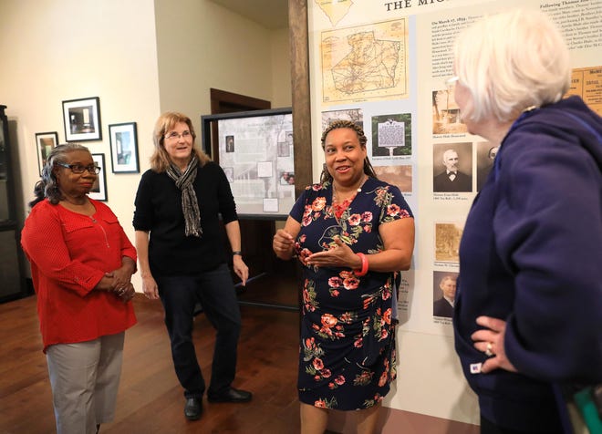 Tatanya Peterson, second from right, who spent 13 years researching her family history, talks to people on Saturday about the new exhibit that features her four-times great grandparents, Hampton and Grace Hathcock, who were enslaved at the plantation of James Chesnut near Alachua, during the grand opening of the exhibit called “Reclaiming Kin: Once Lost , Now Found,” on display at the Historic Haile Homestead, west of Gainesville. The new exhibit features the research of Peterson and Karen Kirkman, second from left, of Historic Haile Homestead and highlands Peterson's ancestors, including her mother Martha Lumpkins Miller, at left. [Brad McClenny/Staff photographer]
