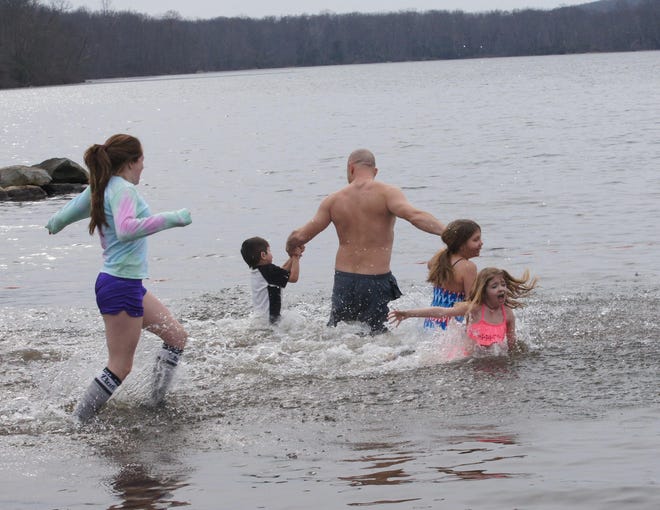 Mackenzie Foster, 7, reacts to the water of Fairfiew Lake on Sunday, Feb. 17, as she and her mother, Ashley Riley, left, of Blairstown, participate in the third annual Fairview Lake YMCA fund-raiser. In the middle are, from left, Felix Waclawski, 5, Maciek Waclawski and Amelia Waclawski, 9, also of Blairstown. [Photo by Bruce A Scruton/New Jersey Herald (NJH)]