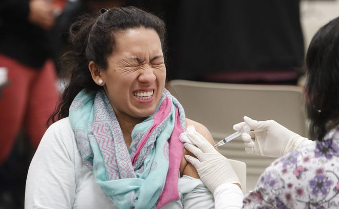 Ana Farfan reacts to getting an influenza vaccine shot at Eastfield College in Mesquite, Texas, last month. [LM Otero/AP]