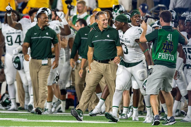 Michigan State Spartans head coach Mark Dantonio and tailback L.J. Scott (3) react as time runs out against the Notre Dame Fighting Irish at Notre Dame Stadium. MSU won 36-28. Michigan State is reportedly investigating allegations of NCAA violations made by a former football staffer in a lawsuit. [Matt Cashore/USA TODAY Sports]