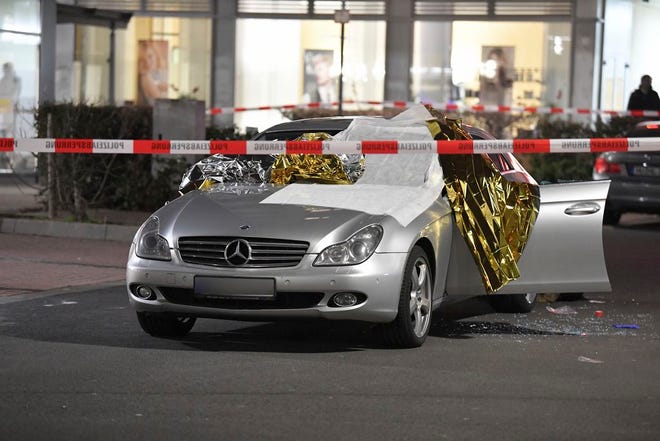 A car that was damaged in a shooting is covered in thermo foil is parked in front of a bar at the scene in Hanau, Germany early Thursday, Feb. 20, 2020. German police say several people were shot to death in the city of Hanau on Wednesday evening. (Boris Roessler/dpa via AP)