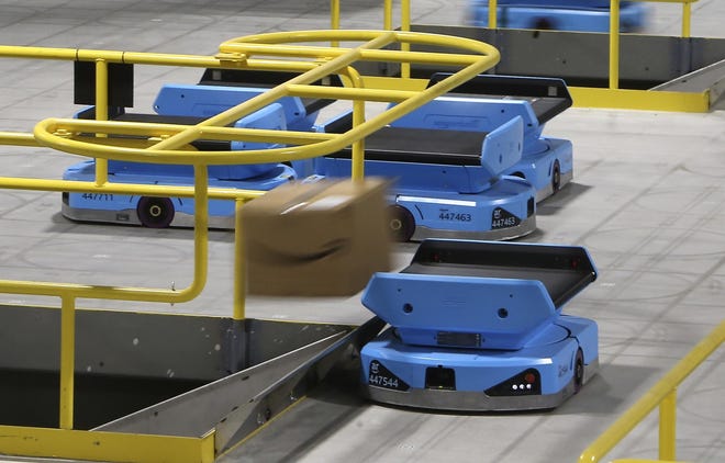 FILE - In this Dec. 17, 2019, file photo an Amazon robot sends a package down a chute, transporting packages from workers to chutes that are organized by zip code, at an Amazon warehouse facility in Goodyear, Ariz. Amazon.com reports financial results on Thursday, Jan. 30, 2020. (AP Photo/Ross D. Franklin, FIle)