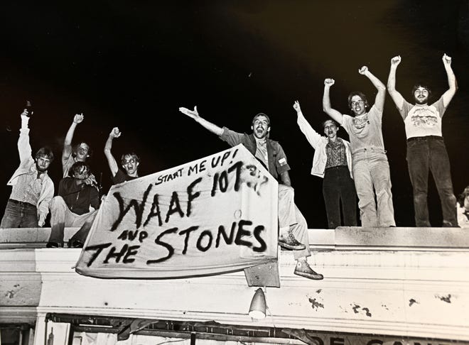 Young adults hold a hand-made WAAF sign from a rooftop in 1981 [T&G File/1981]