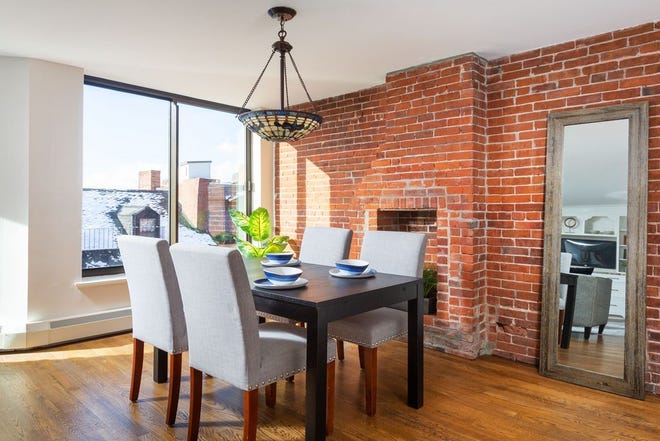 The dining space is enriched with a Tiffany-style stained-glass bowl light fixture and an exposed brick wall with the vestige of a fireplace (closed off) in an old chimney flue.