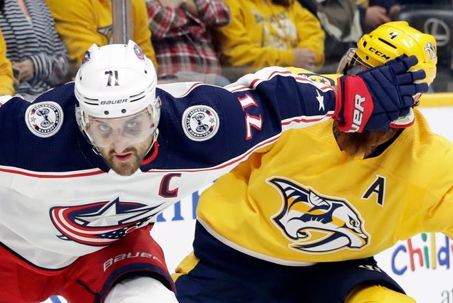 Blue Jackets captain Nick Foligno, sporting two black eyes from taking a puck to the face in Thursday's game, fends off Predators defenseman Ryan Ellis during Saturday night’s game. [Mark Humphrey/The Associated Press]