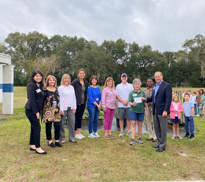 Thomas B. Fleishel, far right, presents Julie Warner with a donation to support Blue Lake Elementary School’s garden project. (Photo provided)