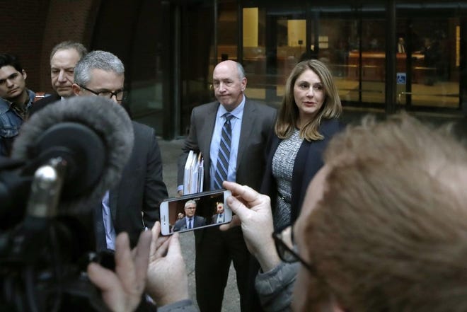 Attorney John Littrell, left and on the screen at center, speaks to the media as client Michelle Janavs, right, stands beside attorney Thomas Bienert, second from right, outside federal court, Tuesday, Feb. 25, 2020, in Boston. Janavs was sentenced to five months in prison for trying to cheat and bribe her daughters' way into college as part of a nationwide college cheating scam. (AP Photo/Elise Amendola)