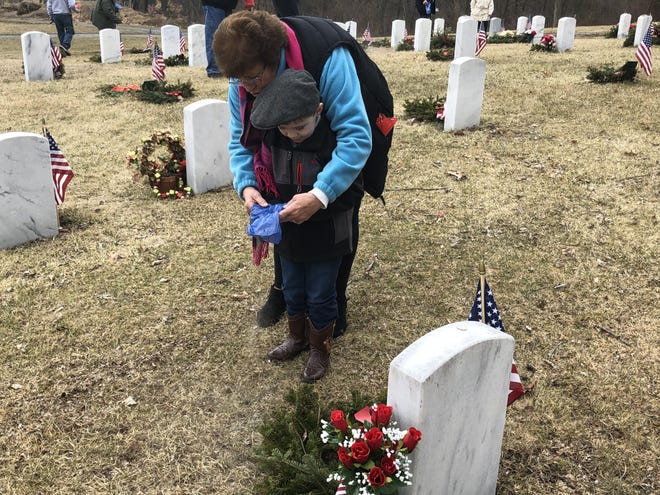 Four-year-old Joseph Kaegi, with help from his grandmother, Rosemary Fuchs, of Wantage, sprinkles ashes from a previous flag retirement ceremony on the grave of his grandfather, Vietnam War veteran Kenneth Fuchs, following a ceremony at the Northern New Jersey Veterans Memorial Cemetery Tuesday, Feb. 25. [Photo by Kyle Morel/New Jersey Herald (NJH)]