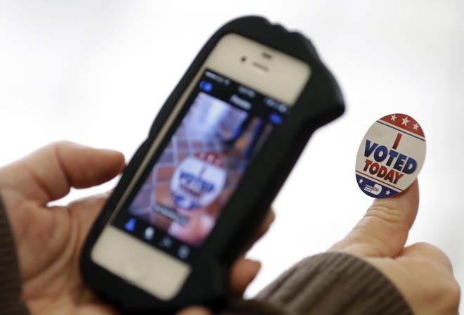 A voter photographs her "I Voted Today" sticker after casting her ballot on the first day of early voting in 2014. [AP Photo/Lynne Sladky, File]