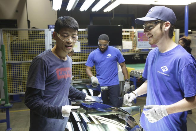 Wong He, left, works with Kenny Taylor, center, and Jarred Gibson in the furnace tempering area of the Fuyao Glass America factory in the Dayton suburb of Moraine. The image was released by Netflix from its documentary "American Factory." [Aubrey Keith/Netflix via AP]