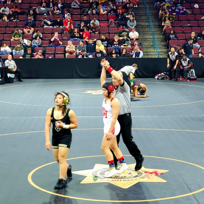Oak Hills’ Athena Willden, center, has her arm raised after winning a match at the CIF State Girls Wrestling Championships in Bakersfield on Thursday. [Photo courtesy of Oak Hills High School]