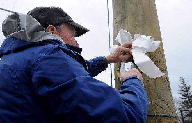 Malcolm Astley, father of Lauren Dunne Astley, who was murdered by her ex-boyfriend in 2011, attaches a white ribbon to telephone poles on Rte. 27 in Wayland in March 2017, in honor of the White Ribbon Campaign and the Lauren Dunne Astley Memorial Fund.  [Daily News and Wicked Local Staff File Photo]