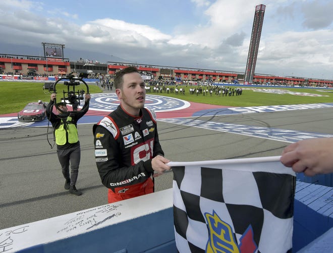 Alex Bowman accepts the checkered flag from an official after winning the NASCAR Cup Series race Sunday in Fontana, Calif. [Will Lester/The Associated Press]