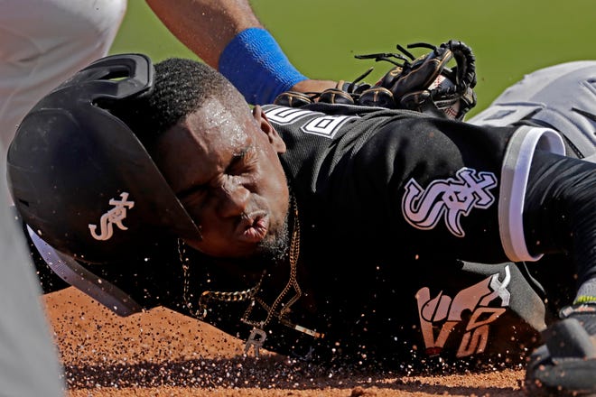 Chicago White Sox's Luis Robert is tagged by Texas Rangers third baseman Todd Frazier after sliding back to third on a double play hit into by Chicago White Sox's Adam Engel during the second inning of a spring training baseball game Saturday, Feb. 29, 2020, in Surprise, Ariz. Robert was ruled out at home on the play. (AP Photo/Charlie Riedel)