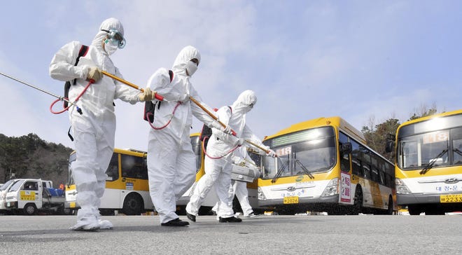 Workers wearing protective gears spray disinfectant as a precaution against the coronavirus at a bus garage in Gwangju, South Korea, Tuesday, March 3, 2020. China's coronavirus caseload continued to wane Tuesday even as the epidemic took a firmer hold beyond Asia, with three countries now exceeding 1,000 cases and the U.S. reporting its sixth death. (Park Chul-hong/Yonhap via AP)
