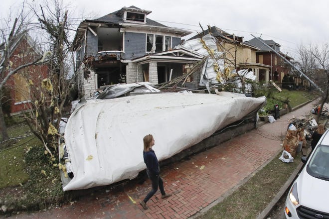 A roof from a nearby business lies in the front yard of a home Wednesday in Nashville, Tenn. Residents and businesses face a huge cleanup effort after tornadoes hit the state Tuesday, killing 24 people and leaving many others missing. [Mark Humphrey/The Associated Press]