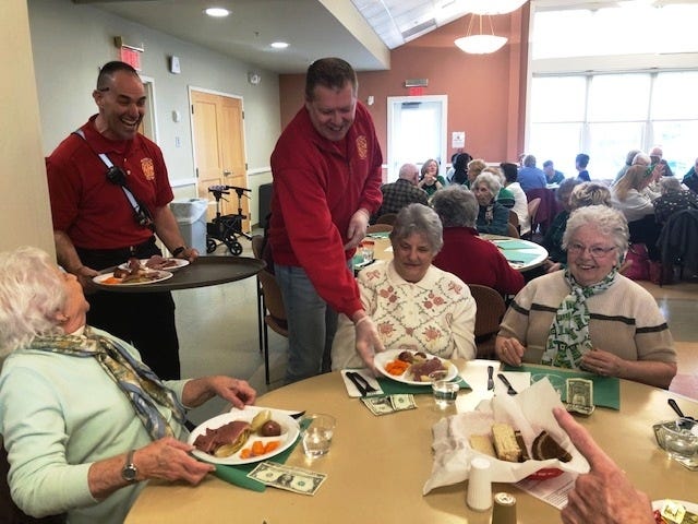 Franklin firefighter/paramedic Paul Molla, left, and fire Capt. Chuck Allen serve up plates of corned beef and cabbage to seniors during the union's inaugural St. Patrick's luncheon at the Franklin Senior Center.  [Wicked Local Staff Photo / Heather McCarron]