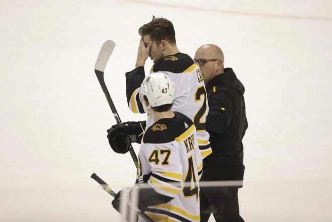 Bruins defenseman Brandon Carlo, center, is helped off the ice after suffering a head injury during the second period of Thursday’s game against the Panthers. He was replaced by John Moore for Saturday’s game against the Lightning. [AP / Wilfredo Lee]