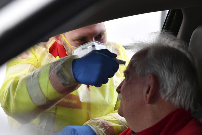 A member of the medical staff measures the temperature of a traveller at a autobahn park place near Gries am Brenner, Austrian province of Tyrol, at border crossing with Italy on Tuesday, March 10, 2020. Austria authorities started on random checks of arriving vehicles at the border crossings with Italy in reaction to the outbreak of the new coronavirus in Europe, particularly in Italy. As part of the move, officials measure the temperatures of some passengers in cars, trucks and buses. For most people, the new coronavirus causes only mild or moderate symptoms, such as fever and cough. For some, especially older adults and people with existing health problems, it can cause more severe illness, including pneumonia. (AP Photo/Kerstin Joensson )