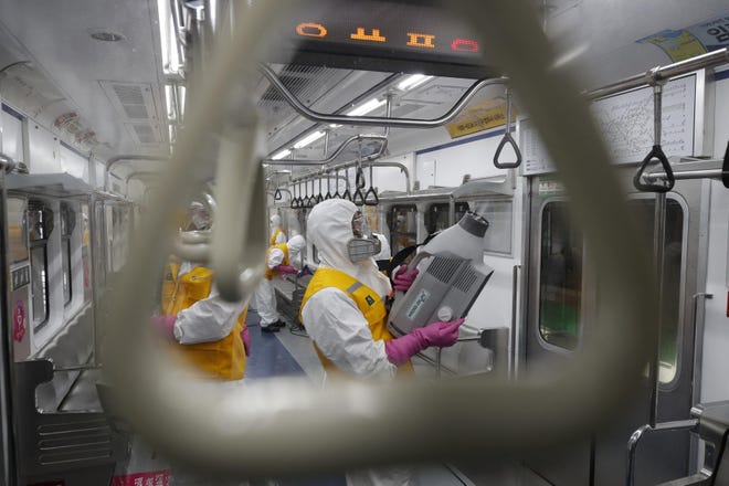 Workers wearing protective gears disinfect as a precaution against the new coronavirus at a subway car depot in Seoul, South Korea, Wednesday, March 11, 2020. For most people, the new coronavirus causes only mild or moderate symptoms, such as fever and cough. For some, especially older adults and people with existing health problems, it can cause more severe illness, including pneumonia. (AP Photo/Lee Jin-man)