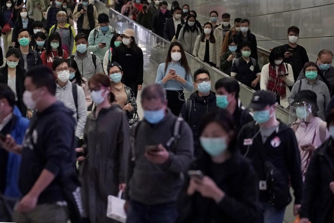 People wear face masks as a precaution against the COVID-19 illness as they walk inside a subway station during rush hour in Hong Kong, Wednesday, March 11, 2020. For most, the coronavirus causes only mild or moderate symptoms, such as fever and cough. But for a few, especially older adults and people with existing health problems, it can cause more severe illnesses, including pneumonia. (AP Photo/Kin Cheung)