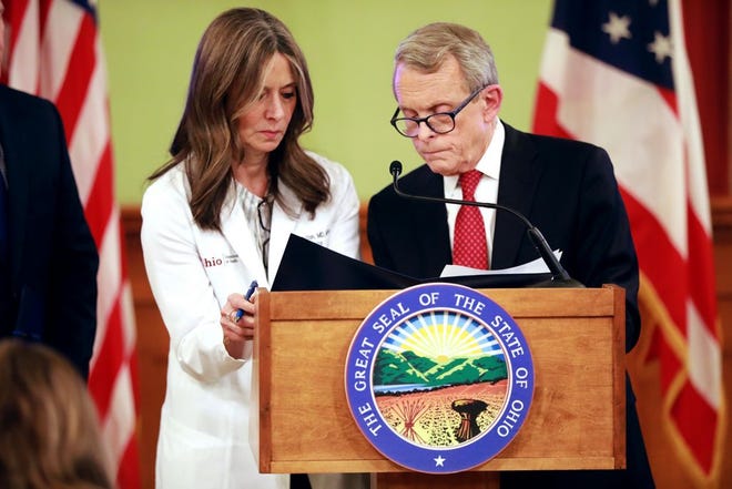 Ohio Gov. Mike DeWine signs an order banning large groups of 100 or more, along with Dr. Amy Acton (left), the head of the Ohio Department of Health, during a press conference updating the public on COVID-19 on March 12 at the Ohio Statehouse.