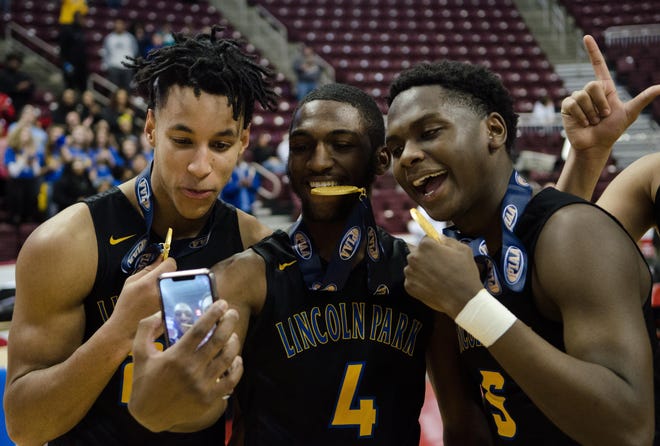 Lincoln Park players, from left, Keeno Arrington, Casey Oliver and Isaiah Smith take selfies with their gold medals after winning the PIAA Class 3A basketball championship in Hershey.
