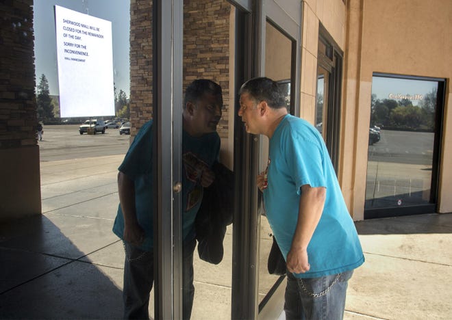 Customer Ricky Hernandez looks through the glass doors to entrance to Sherwood Mall in Stockton after the mall closed Thursday in the wake of a shooting that killed a teenager on Wednesday night. [CLIFFORD OTO/THE RECORD]