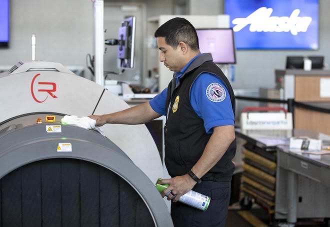A TSA screening officer uses Lysol disinfecting spray to clean equipment at Austin-Bergstrom International Airport. He said the cleaning is standard protocol. [JAY JANNER/AMERICAN-STATESMAN]
