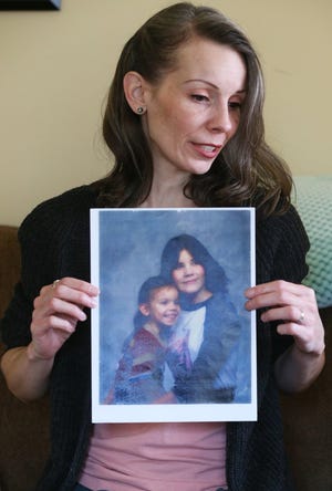 Leila Hanes, 42, holds a childhood photo of herself with her slain sister, Rachael M. Johnson. She was 3 when the photo was taken and Rachael was 14. Hanes keeps a framed copy of the photo in her living room. [Mike Cardew/Beacon Journal]