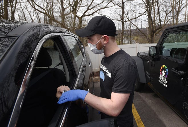 Jeffrey Jordan, a medical assistant, tests the blood oxygen level of a man at a coronavirus drive-thru testing site Monday at the Central Outreach Wellness Center in Aliquippa. By early afternoon, the center had triaged more than 50 people by screening symptoms. They will open again at 9 a.m. Tuesday and are hoping to have more tests available. [Sally Maxson/For BCT]