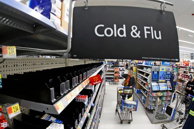 FILE - In this Friday, March 13, 2020, file photo, a woman looks at the few selections remaining in the cold and flu aisle of a Walmart near Warrendale, Pa. Walmart, the nation’s largest retailer and private employer, said late Saturday, March 14, 2020, it is limiting store hours to ensure they can keep sought-after items such as hand sanitizer in stock amid the coronavirus pandemic. (AP Photo/Gene J. Puskar, File)