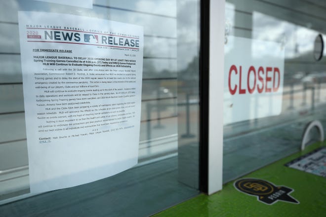 Closed signs and MLB news releases are displayed on box office windows outside of Peoria Stadium, home of the San Diego Padres and Seattle Mariners on March 13, 2020 in Peoria, Ariz. Major League Baseball cancelled spring training games and has delayed opening day by at least two weeks due to COVID-19. (Christian Petersen/Getty Images/TNS)