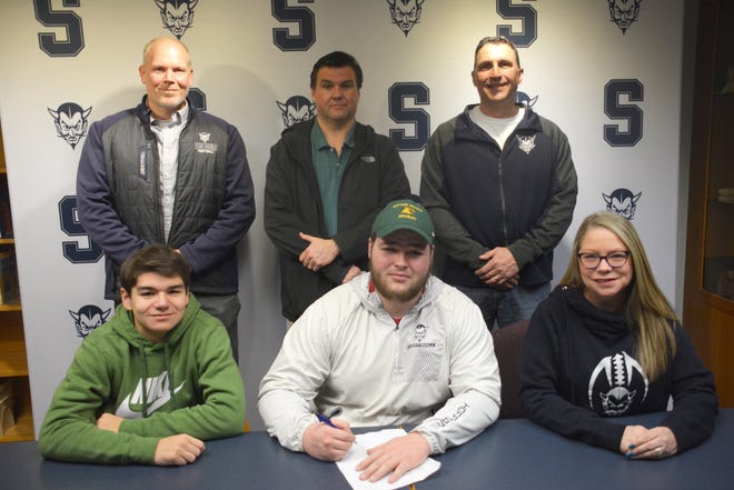 Saullt High's Thalen Hoffman, front row center, has signed to play football at Northern Michigan University. Pictured front row left are his brother Keenan Hoffman, and front right, his mother Tan'A Hoffman; and back row, from left; Sault assistant football coach Gordi Campbell, Thalen's father D.J. Hoffman, and Sault head football coach Scott Menard. [Rob Roos/Sault News]