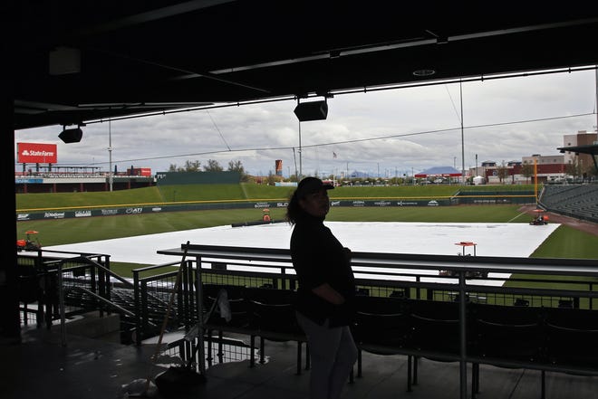 A worker looks out onto the tarp-covered field after a spring training baseball game between the Los Angeles Dodgers and the Chicago Cubs was canceled for inclement weather at Sloan Park in Mesa, Ariz., Thursday, March 12. Major League Baseball is delaying the start of its season because of the coronavirus outbreak. (AP File Photo/Sue Ogrocki)