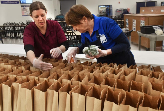 Teresa Wolly, left, and Joan Laundry of the Oyster River School Child Nutrition Dept. pack food items in bags which will be delivered to students during the time schools are closed due to coronavirus. [Deb Cram/Fosters.com]