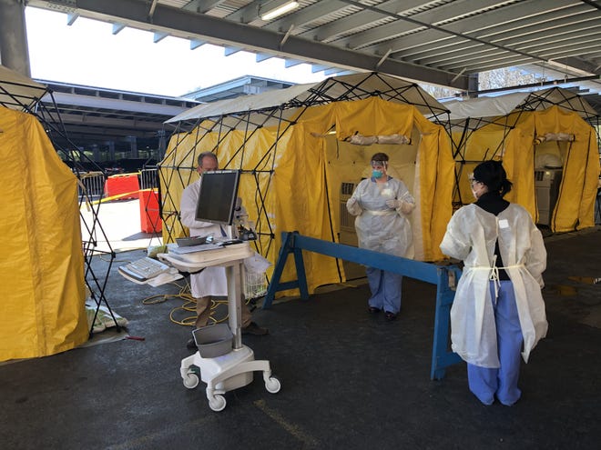 Newton-Wellesley Hospital clinicians are seen working at the drive-through tents on top of the employee garage where they are testing people for COVID-19. [Courtesy photo]