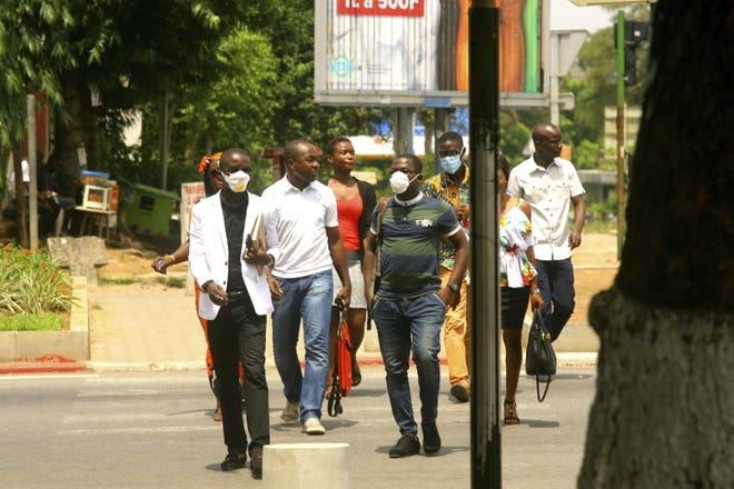 Residents of Abidjan, Ivory coast, wear masks Thursday to protect themselves from the coronavirus as they walk along a street. Some countries around the world lack the equipment and trained health workers to respond to the threat of COVID-19 virus. For most people, the virus causes mild or moderate symptoms, but for others it causes severe illness. [DIOMANDE BLE BLONDE/THE ASSOCIATED PRESS]